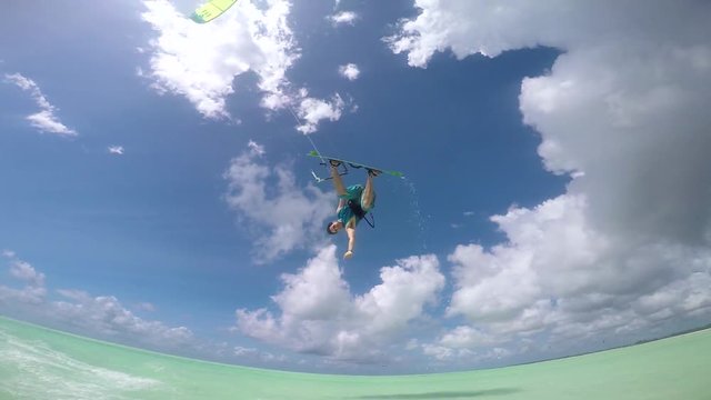 SLOW MOTION: Happy smiling kite surfer jumping over camera showing thumbs up