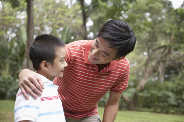 Happy father and son arm around in park