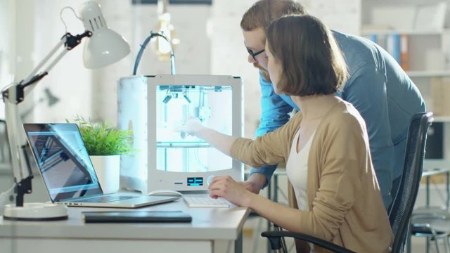 Young Man and Woman Engineers Create Models Using 3D Printer.  Shot on RED Cinema Camera in 4K (UHD).
