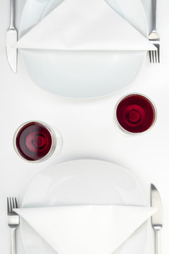Rotwein im Glas auf gedecktem Tisch f&uuml;r zwei Personen, Draufsicht