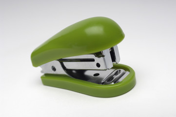 Closeup of green stapler isolated over gray background