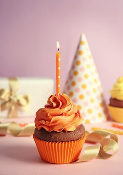 Birthday cupcake and gift box on lilac background