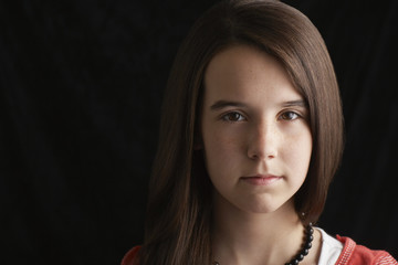 Closeup portrait of confident teenage girl against black background