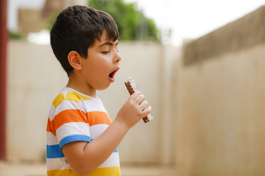 Small Boy Opening His Mouth To Eat Chocolate Bar