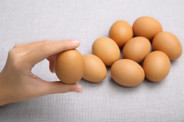 Female hand holding raw egg on light background