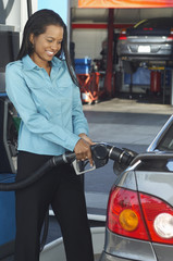 Happy African American businesswoman refueling car at petrol pump