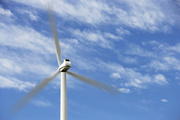 Wind turbine in motion against cloudy sky at wind farm