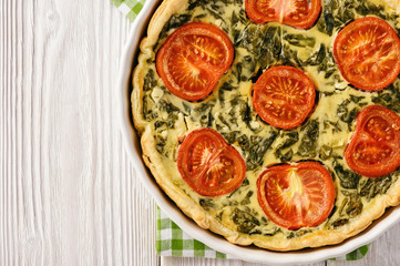 Fototapeta na wymiar Homemade quiche with spinach, feta cheese and tomatoes.