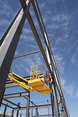 Manual worker working from cherry picker on steel framing structure