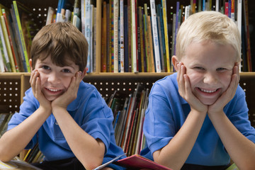 Portrait of two happy schoolboys in school library