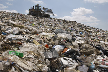 Low angle view of digger working at dumping ground