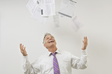 Happy senior businessman throwing bills in the air isolated over white background