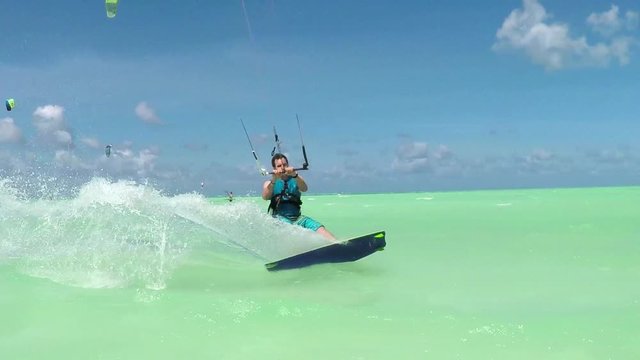 SLOW MOTION: Happy extreme kiter jumping and splashing water drops into camera
