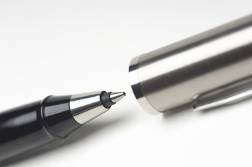 Cropped image of ballpoint pen with cap over white background