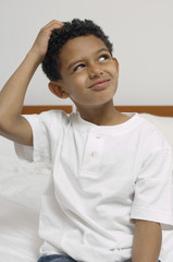 Thoughtful young boy with hand on head looking away