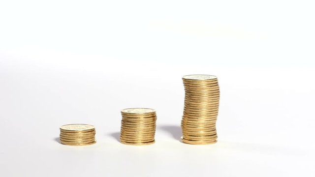 Three piles of golden coins on white background, male hand adds few more on top of one pile, finances, business, carculating money, saving. Close up, 4K Ultra HD.