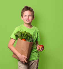 Healthy positive happy child with paper shopping bag full of vegetables