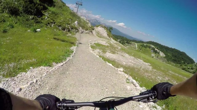FPV: Beginner biker riding downhill on easy rocky flow track in bike park