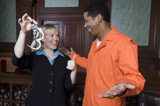 Happy female lawyer with man in prison uniform celebrating his acquittal in court