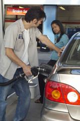 Woman looking at gas station attendant pumping gas into car