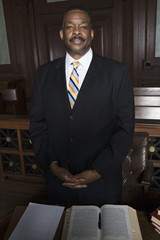 Portrait of African American lawyer standing by table in courthouse