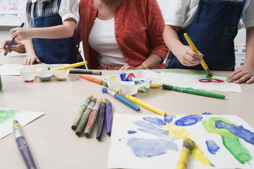 Teacher assisting elementary students while painting in art class