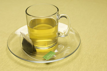 Closeup of teabag on cup and saucer on surface