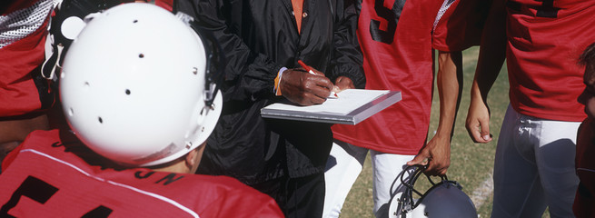 Players standing together with coach writing on paper