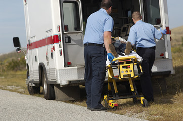 Male paramedics with patient on stretcher by ambulance © MDBPIXS