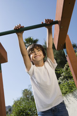 Fototapeta premium Happy boy swaying on a jungle gym