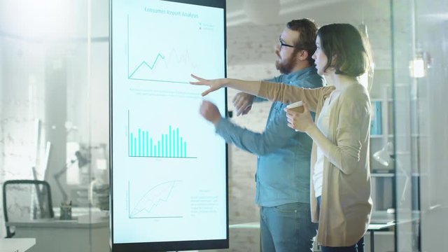 Young Man and Woman Discuss Charts Drawn on Their Electronic Whiteboard. Man Shows Details on the Screen Woman Listens. Shot on RED Cinema Camera in 4K (UHD).