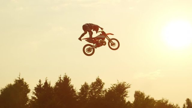 SLOW MOTION: Extreme pro motocross biker jumping freestyle trick over the sun