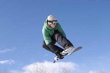 Fototapeta na wymiar Low angle view of male snowboarder performing stunt against blue sky