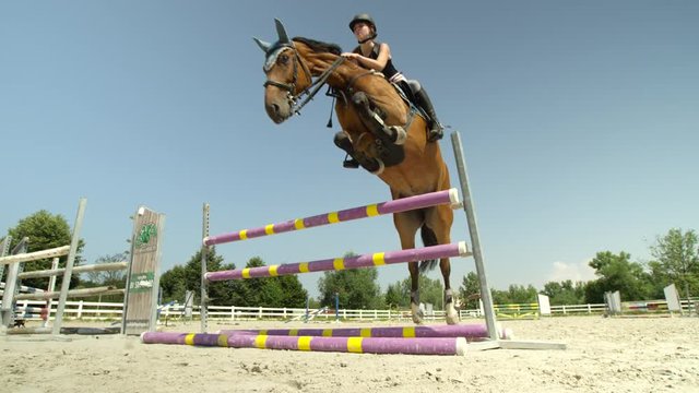 SLOW MOTION: Young rider girl jumping the fence and horse knocks the pole down