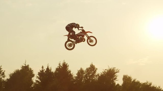 SLOW MOTION: Pro freestyle motocross biker jumping extreme trick over the sun