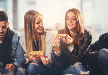 Young people in casual clothes eating pizza, talking