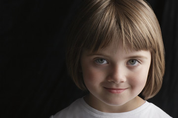 Closeup portrait of adorable little girl smiling isolated on black background