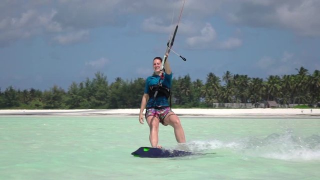 SLOW MOTION:  Smiling young surfer girl kiteboarding in picturesque blue ocean