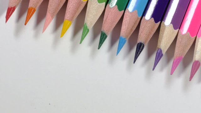 Multicolored sharp ends on wooden pencils lying on white desk, supplies for kids' creativity, drawing is a kind of art. Close up, 4K Ultra HD.