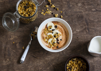 Pumpkin smoothie bowl with banana and granola on wooden table, top view. Delicious healthy breakfast