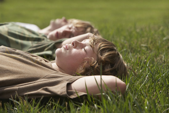 Side view of three young boys relaxing on grass