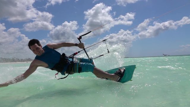 SLOW MOTION CLOSEUP: Cheerful surfer smiling and kiteboarding in tropical lagoon