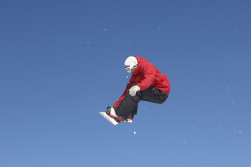 Fototapeta na wymiar Full length of male snowboarder jumping against blue sky