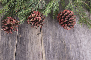 Fir branches with cones on rustic wooden background with space for text