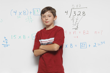 Portrait of a confident male student standing against white board