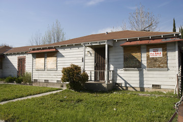 Boarded abandoned house with green lawn not for sale