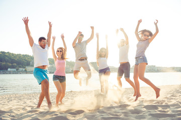 Young friends enjoying  beach party and jumping on summer sunset