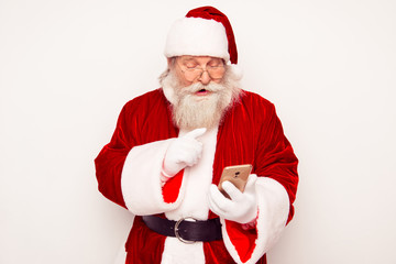 Modern Santa in red costume reading message on smartphone