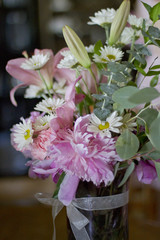 Fototapeta na wymiar Wedding Flower Arrangement - Pink Peonies and Roses, Daisies, and Eucalyptus in a Clear Glass Vase