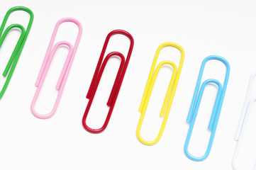 Row of multicolored paperclips over white background